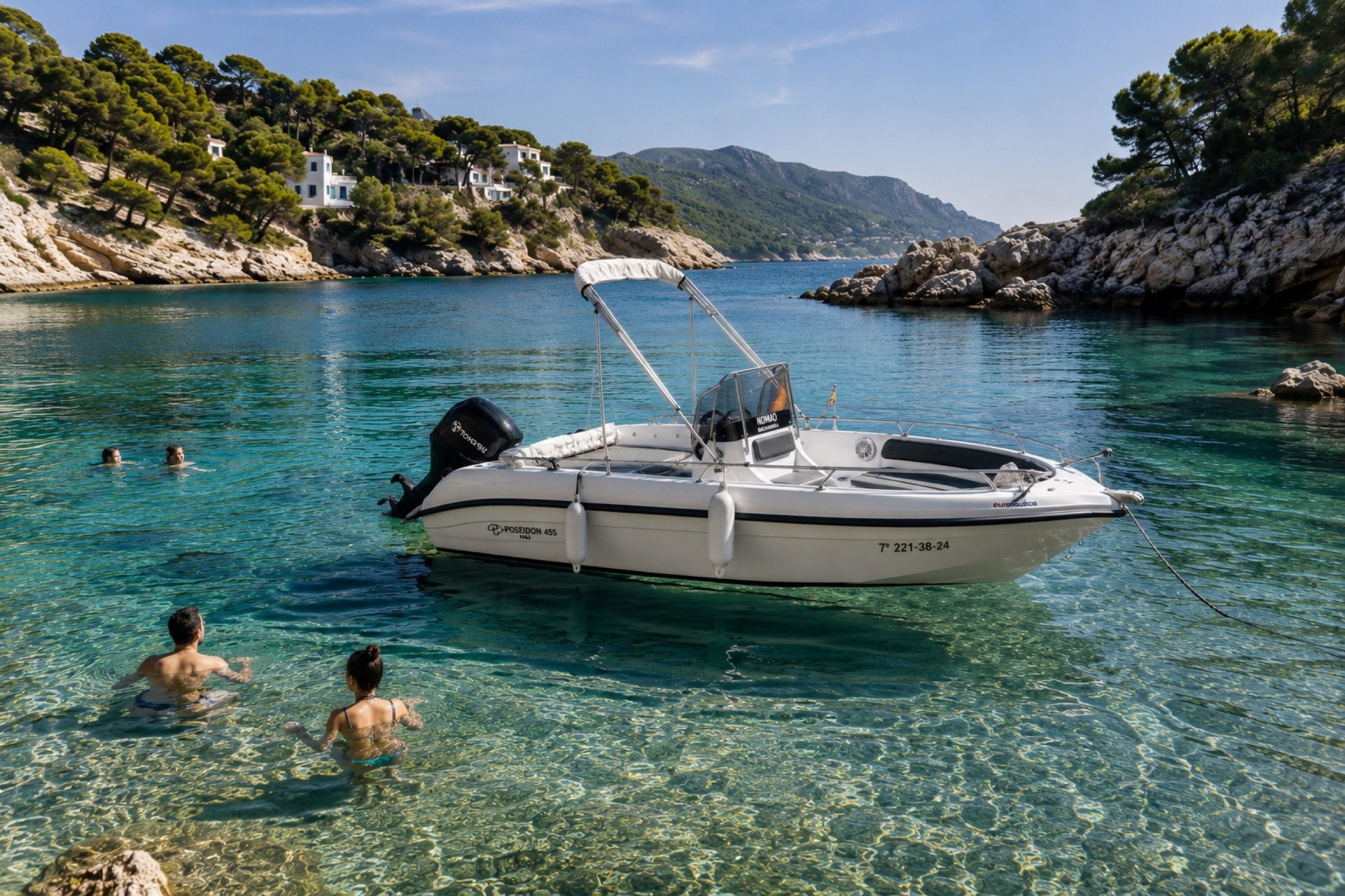 The boat anchored in a clear turquoise cove while people swim around it