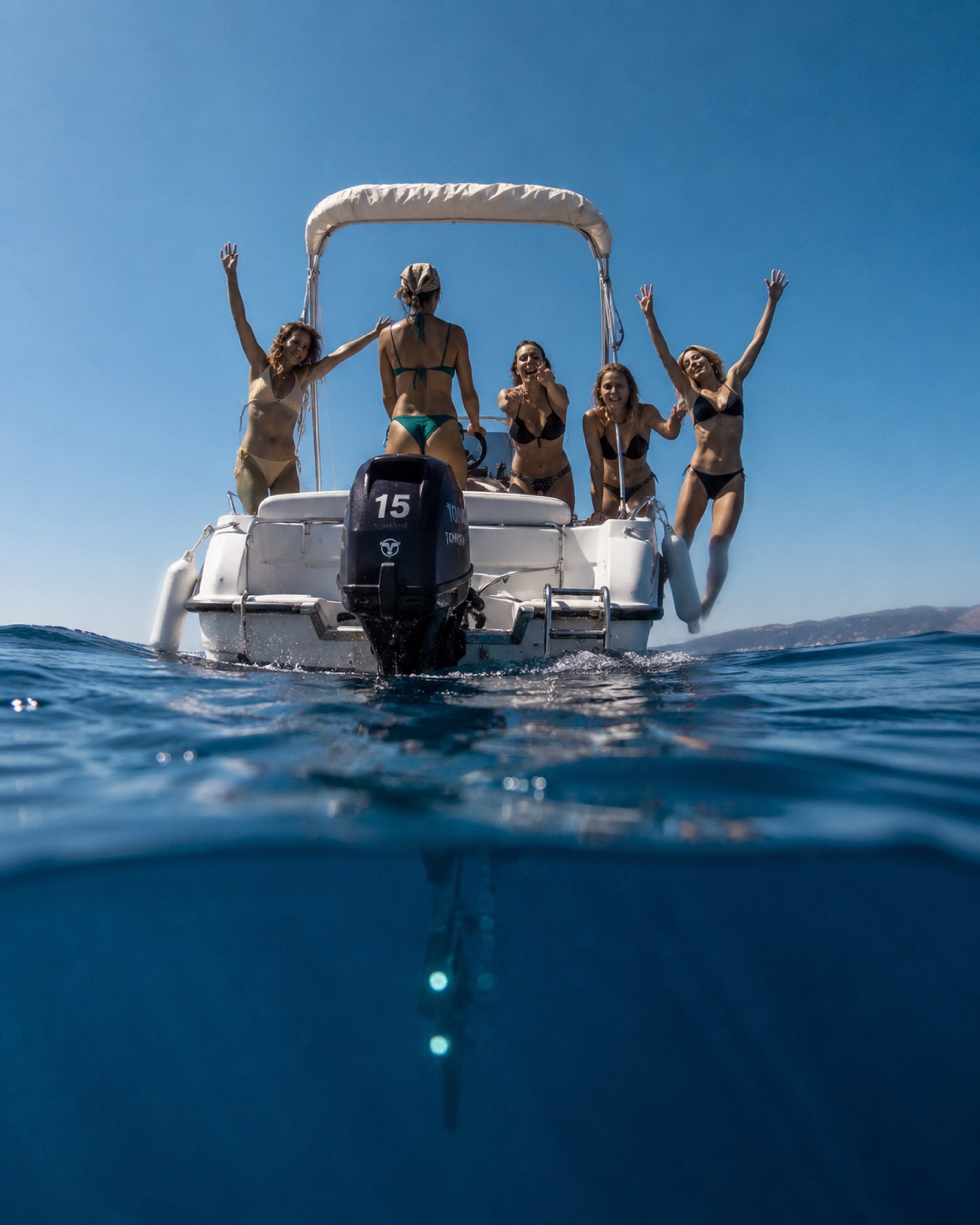A group cheering from the back of the boat, photographed from the water