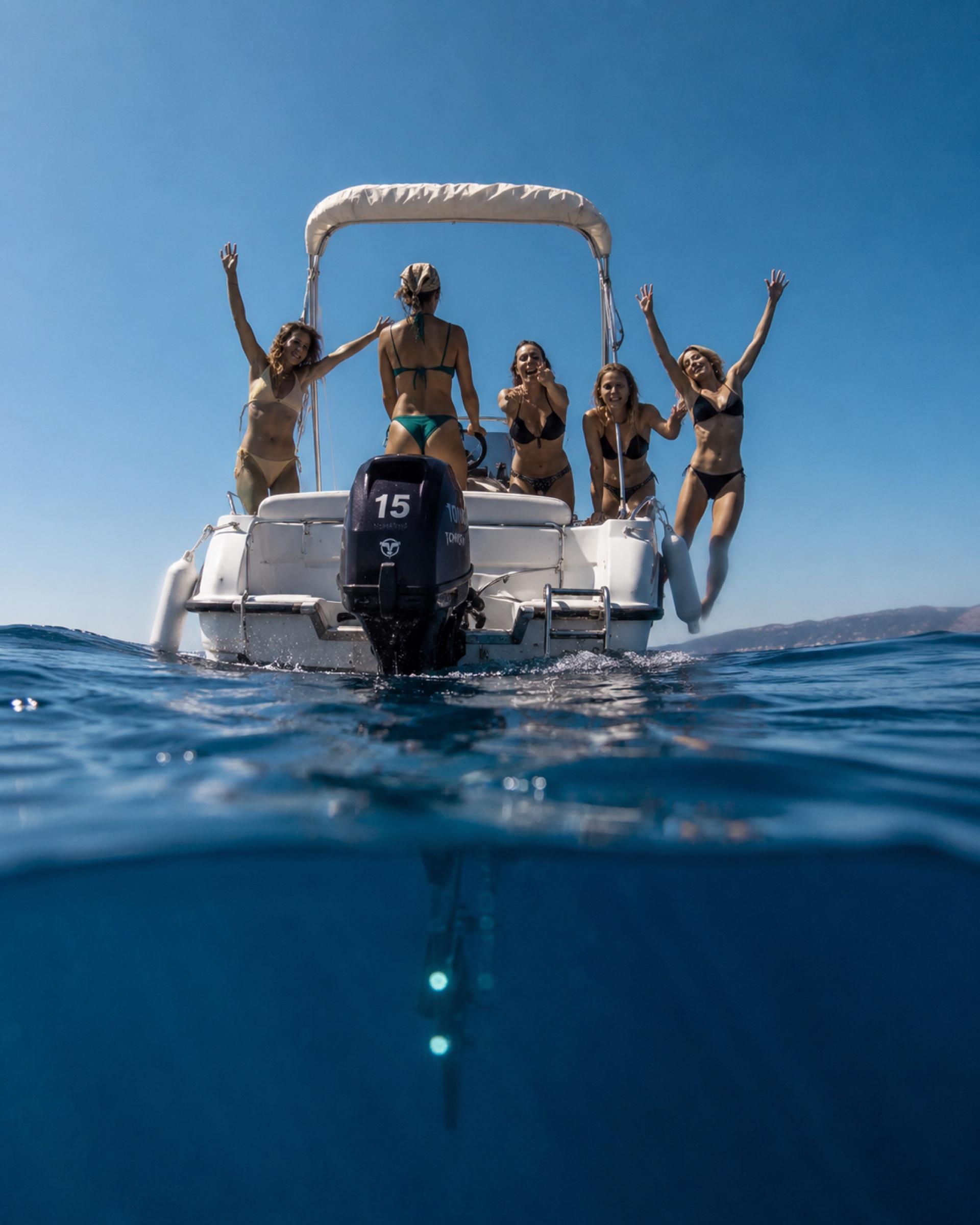 A group cheering from the back of the boat, photographed from the water